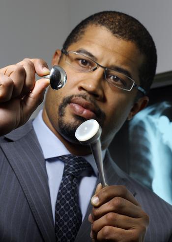 Dr Wiemi Douoguih holds artificial shoulder ball and socket pieces, used in total shoulder replacement surgery.