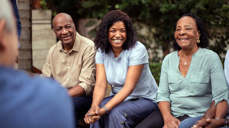 A group of adults laugh while spending time together outdoors.