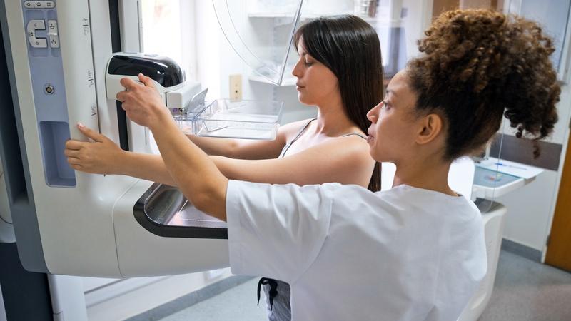 A technician positions a woman at a mammography scanning machine.