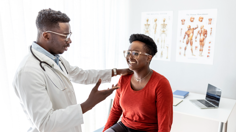 A doctor puts his hand on a patient's shoulder as he explains during an office visit.