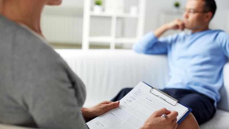 A behavioral health professional talks with a patient in a professional office.