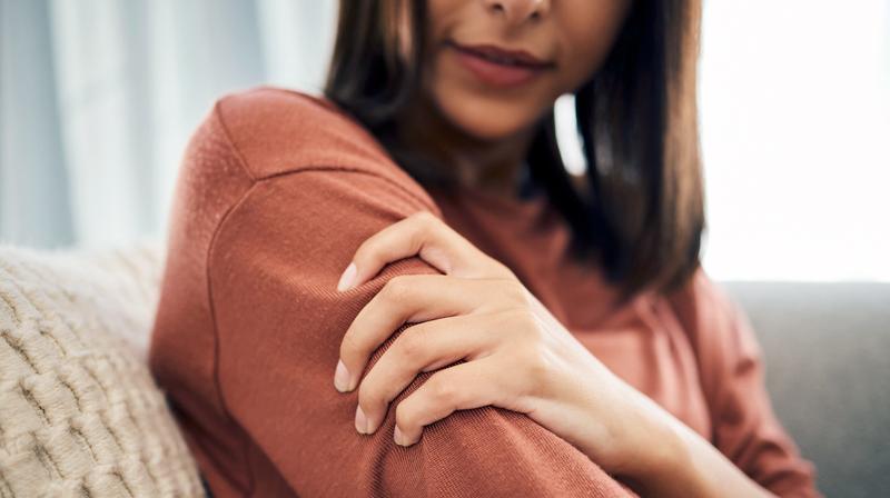 Close up photo of a woman holding her shoulder while experiencing pain.