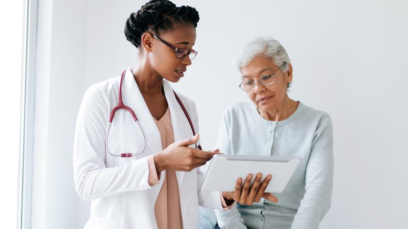 A senior woman talks with her doctor in a clinical setting.
