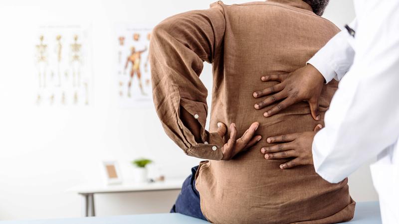 A doctor examine's a patient's lower back during an office visit.