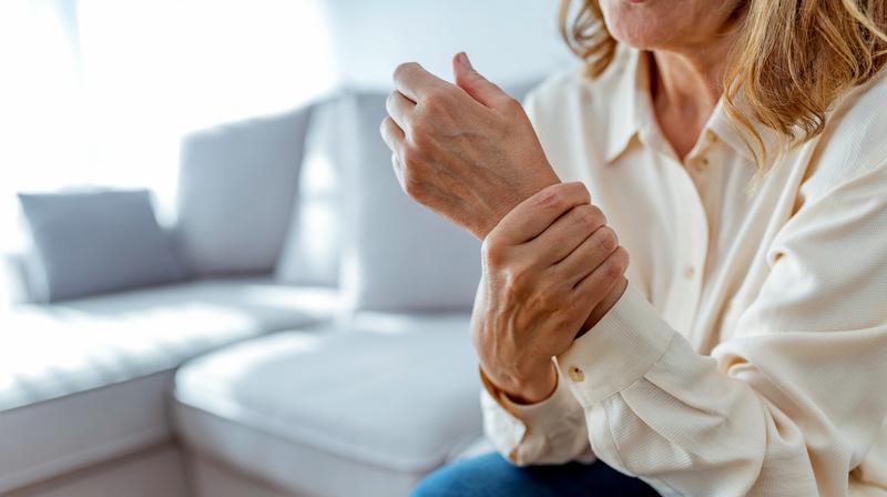 Close up photo of a woman holding her wrist in pain.