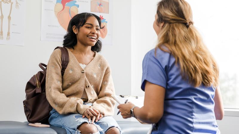 A young patient sits on an exam table in a doctor's office.