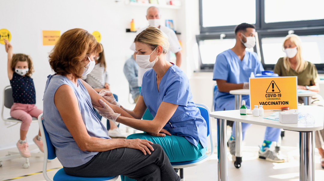 A nurse vaccinates a woman at a community immunization event.