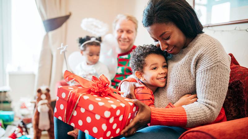 A boy hugs his mother after giving her a Christmas gift.