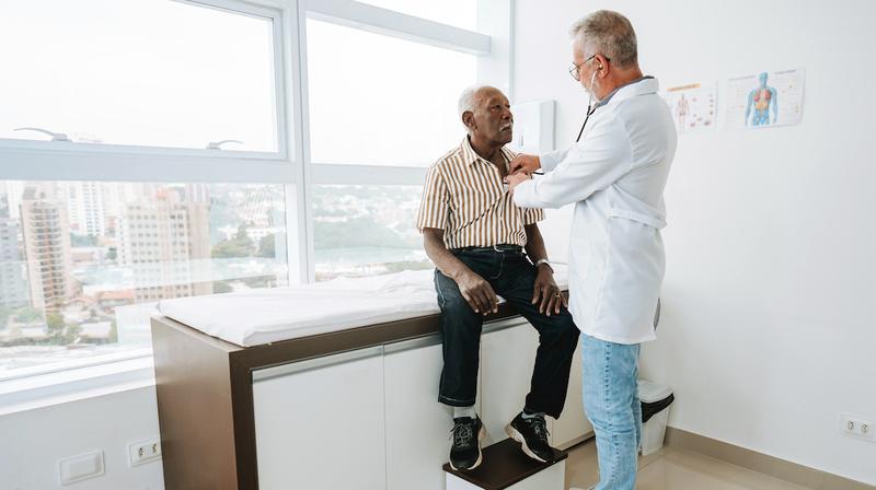 A doctor listens to a patient's heart during an office visit.