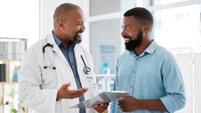 A doctor talks with a male patient in a clinical setting.