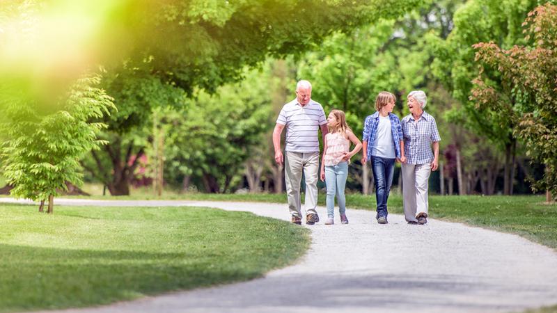 Grandparents go for a walk outdoors with their teenage grandchildren.