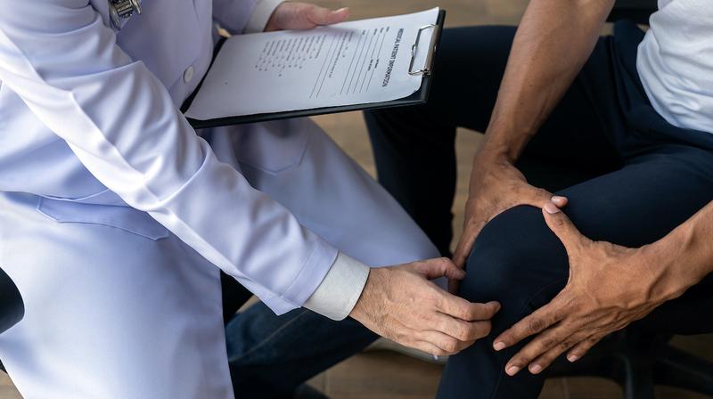 A doctor examines a patient's knee.