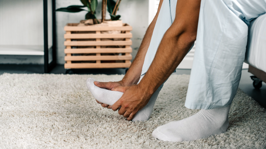 Close up photo of a man holding his foot in pain.