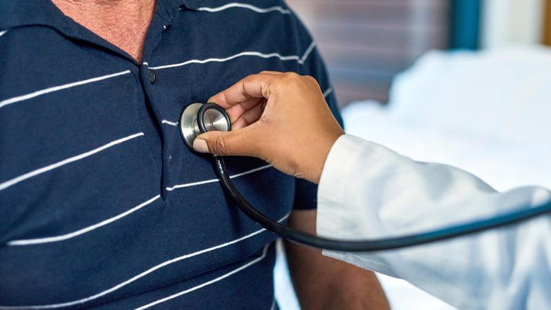 Close up photo of a doctor using a stethoscope listening to a patient's heart.