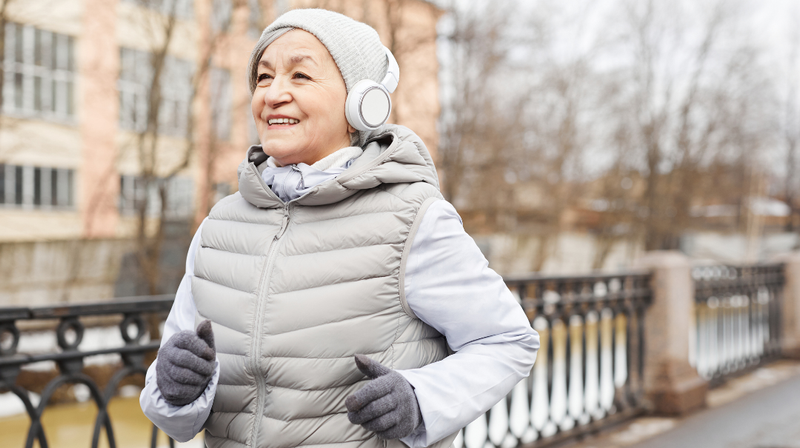 A senior woman runs outdoors in the cold weather.
