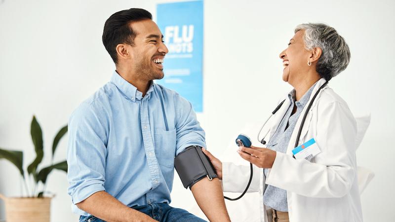 A doctor takes the blood pressure reading of male patient in a clinical setting.