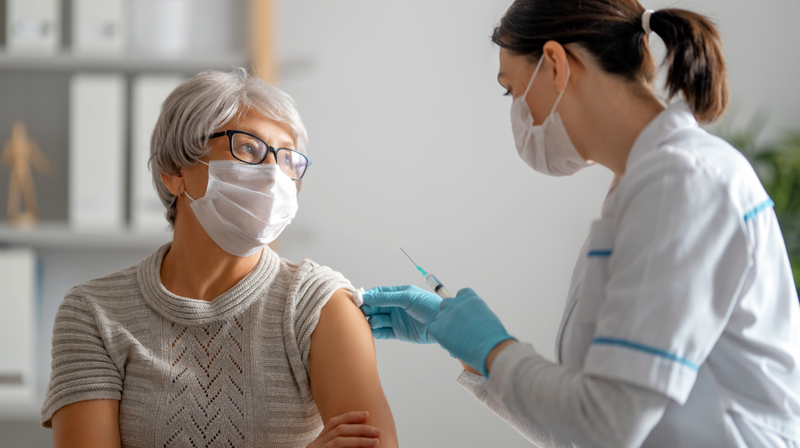 A doctor vaccinates a senior female patient.