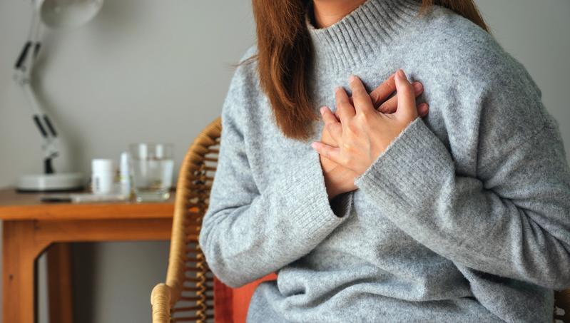 Close up photo of a woman holding her hands on her chest over her heart.