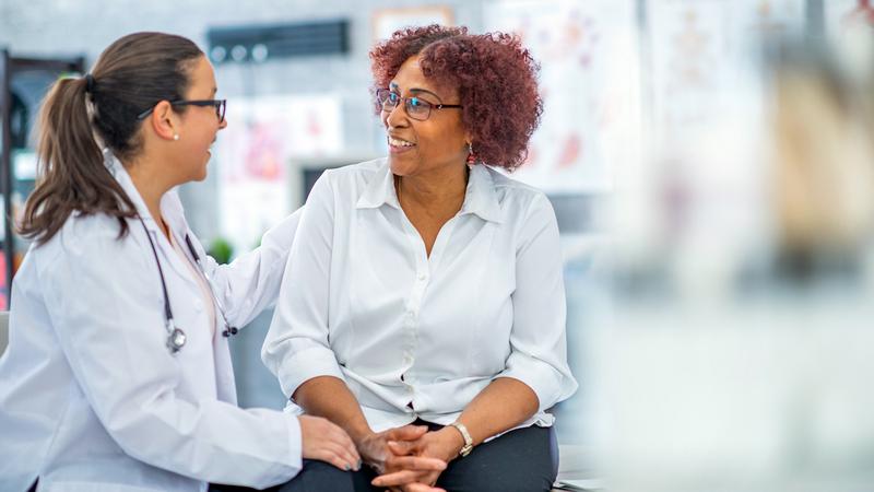 A woman talks with her doctor in a clinical setting.