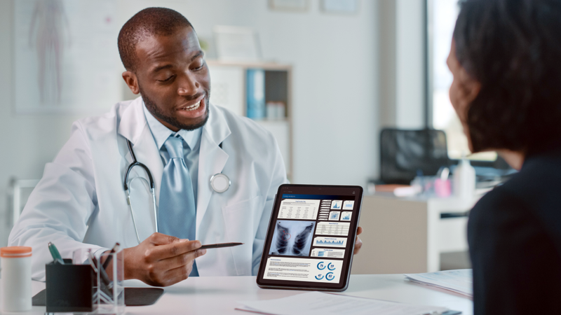 A doctor meets with a patient and shows the results of a lung scan in an office setting.