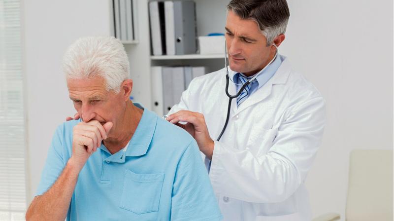 A doctor listens to a patient's lungs during an office visit.