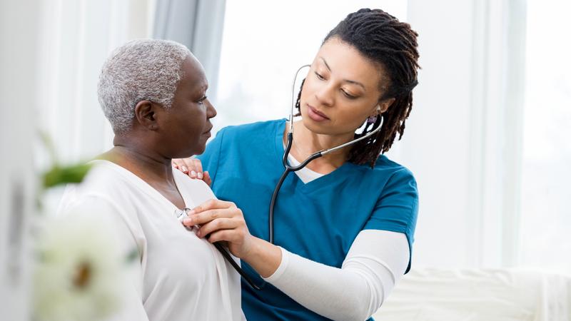 A nurse listens to the heart of a senior woman patient.