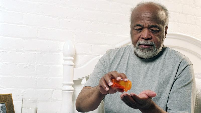 An elderly man takes his prescription medication.