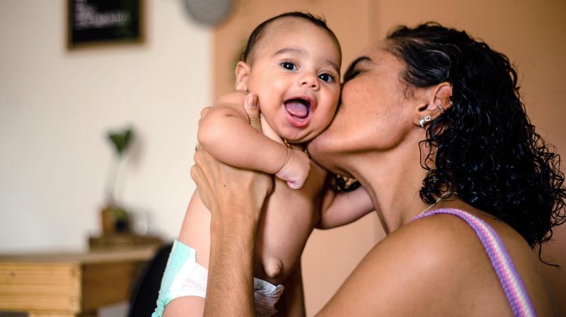 A mother kisses her newborn baby.