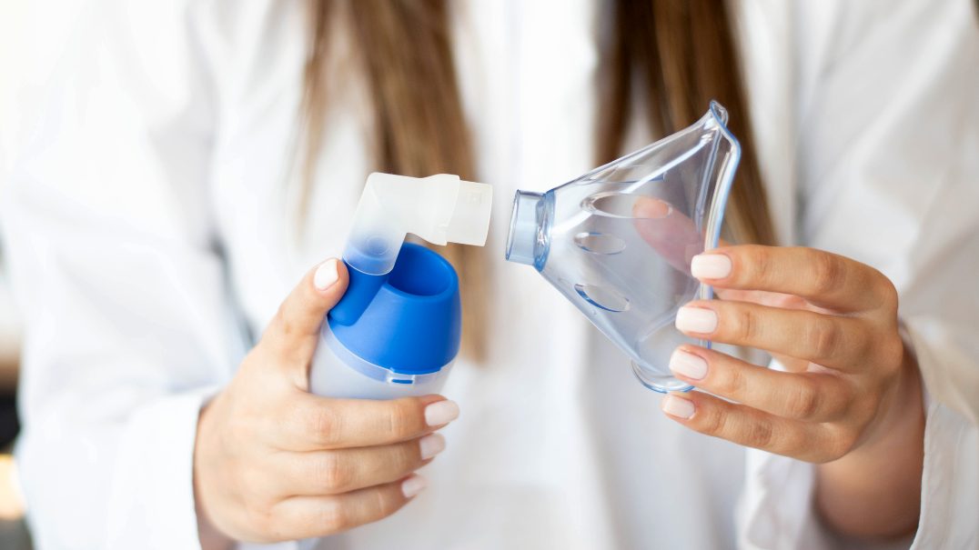 A close up photo of a nurse holding a nebulizer.