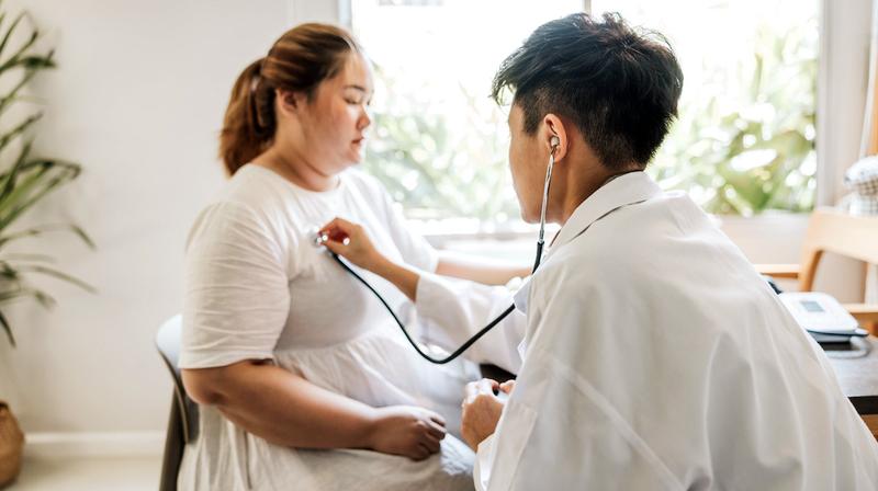 A doctor listens to the heart rate of a patient during an office visit.