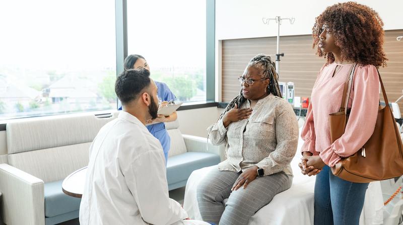 A senior woman and a family member talks with a doctor during an office visit.