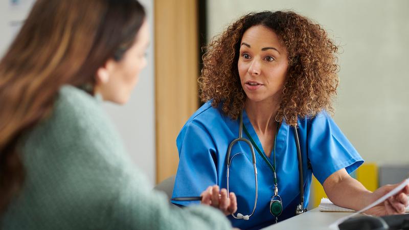 A nurse consults with a patient in a clinical setting.