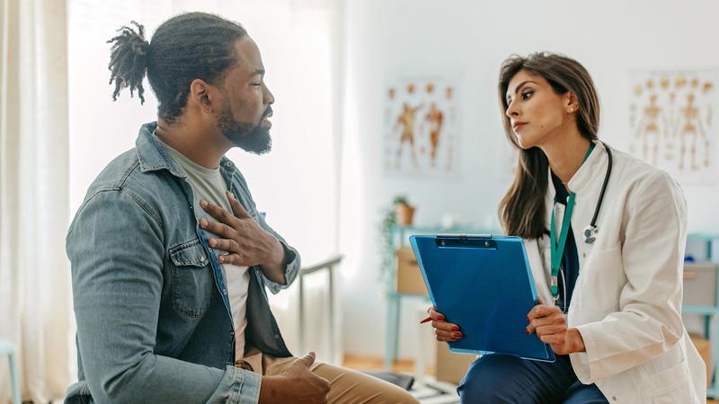 A man talks with his doctor in a clinical setting.