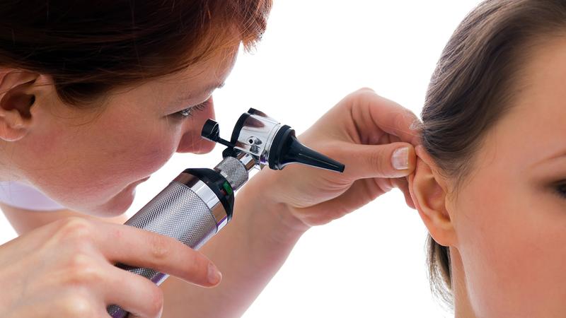 A doctor checks a patient's ear during an office visit.