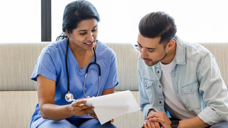 A young adult man talks with a healthcare professional.