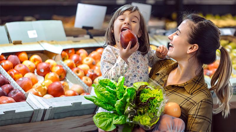 A mother and her young child shop for fresh fruit and vegetables.