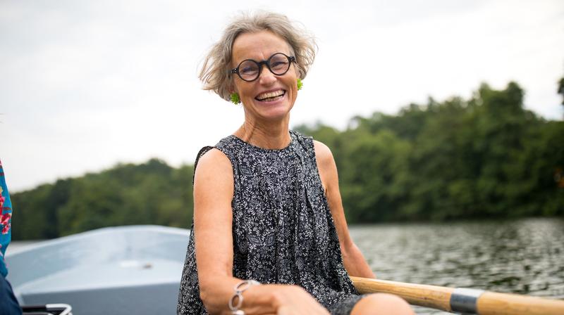 A woman enjoys time on a rowboat at a lake.