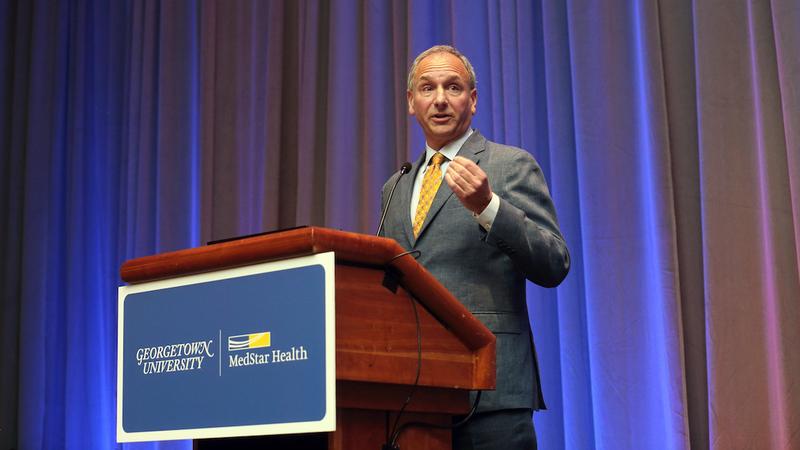 Dr. Neil Weissman speaks at a podium on stage.