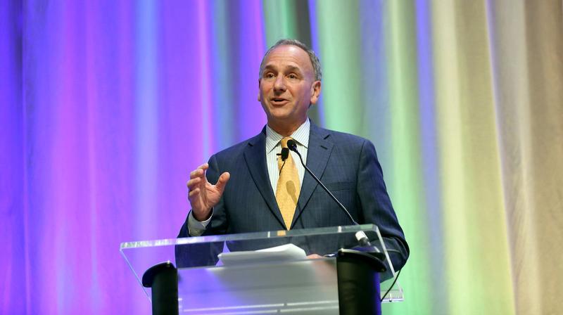 Dr. Neil Weissman speaks at a podium on stage.