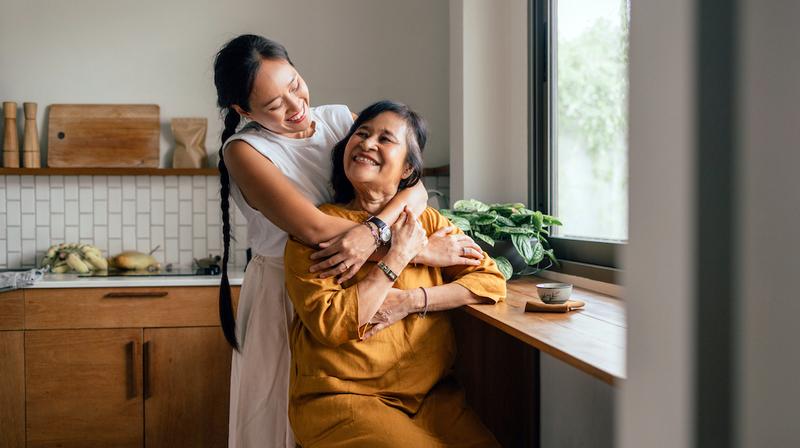 A young woman hugs an older female family member at home.