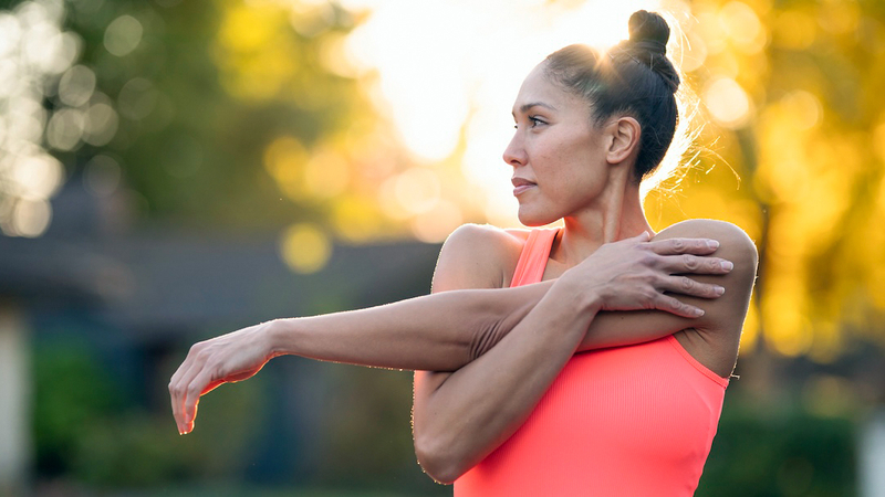 A young woman stretches before her workout outdoors.