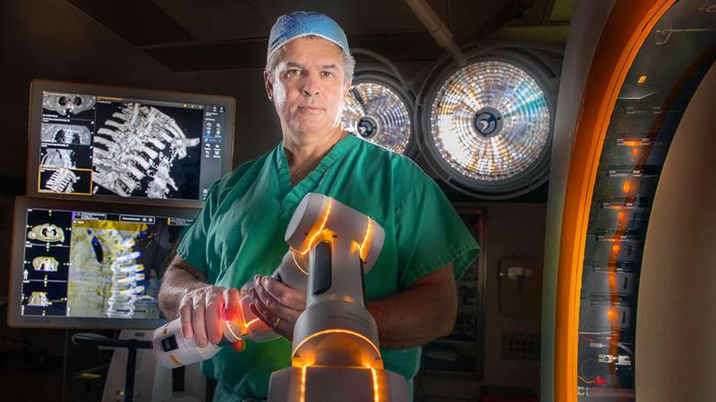 Dr Edward Aulisi stands with a Cirq robotic arm in the operating room at MedStar Washington Hospital Center.