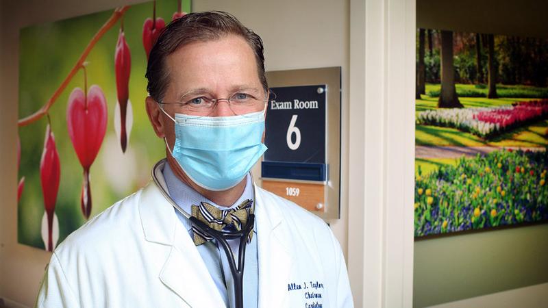 MedStar cardiologist Allen Taylor poses for a portrait in the hallway of a MedStar Health facility. Dr Taylor is wearing a mask and looking at the camera.