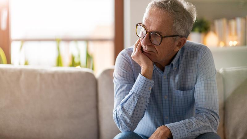 Worried senior man sitting alone in his home