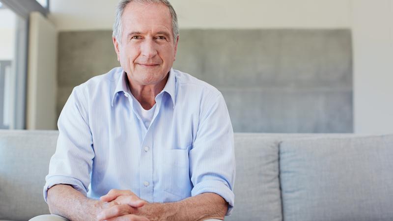 Portrait of a happy senior man sitting on the sofa at home.