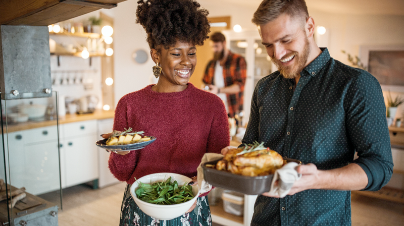 A young couple cooks a healthy meal of chicken and green beans in their kitchen.