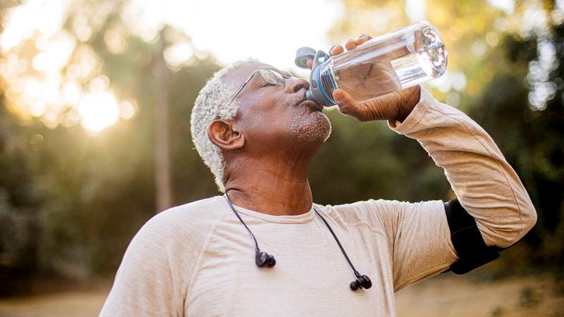 A senior black man takes a drink of water during his workout