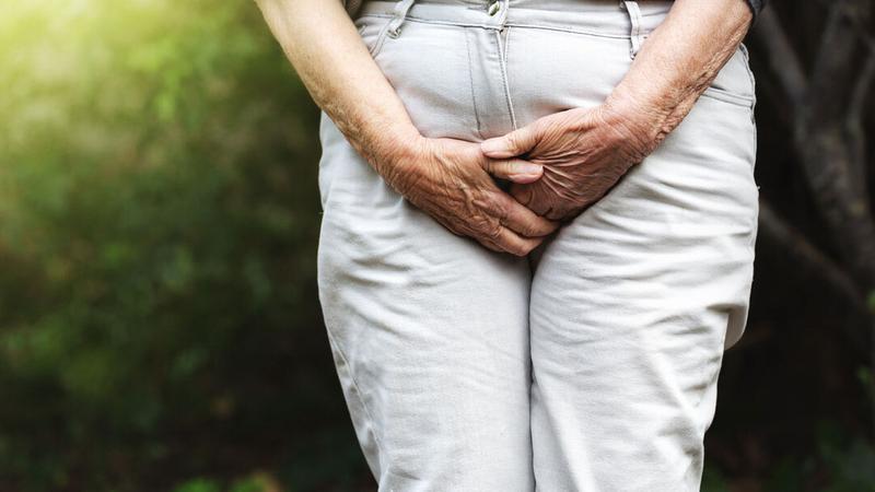 Close up photo of a woman holding her crotch as if she has to urinate.