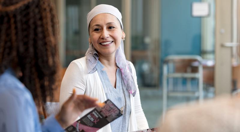 A female cancer patient talks with a female provider in a hospital waiting room.