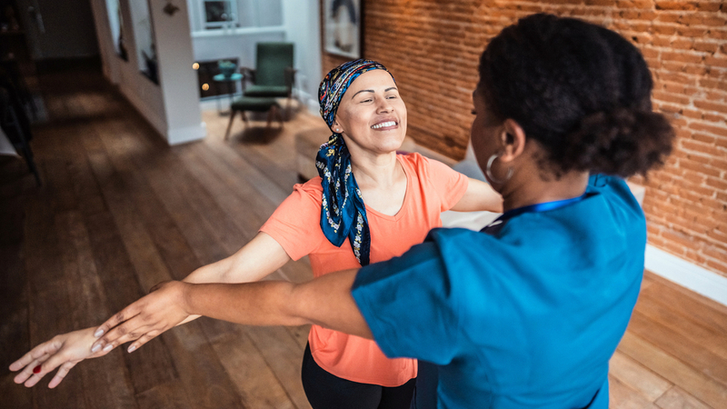 An exercise coach helps a woman who is undergoing cancer treatment.
